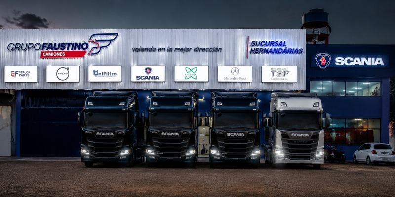 Sucursal Hernandarias de Grupo Faustino al anochecer, con cuatro camiones Scania con los faros encendidos