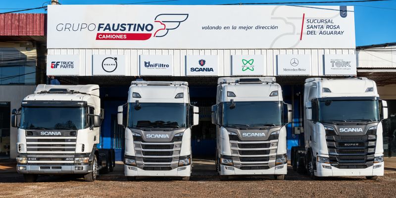 Fachada de la sucursal Santa Rosa del Aguaray con cuatro camiones Scania de distintas generaciones alineados